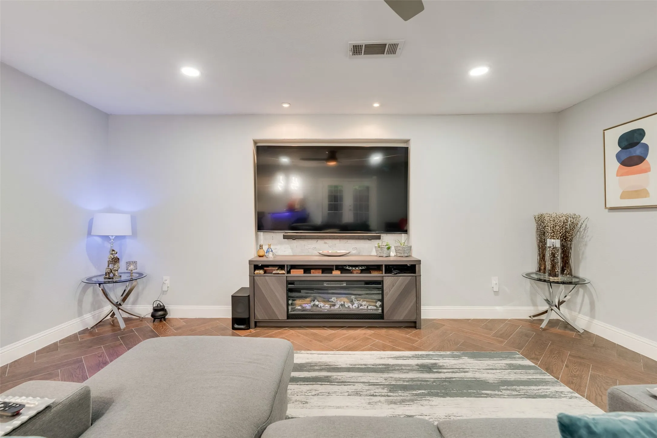 Living room with baseboards, recessed lighting, and a glass covered fireplace