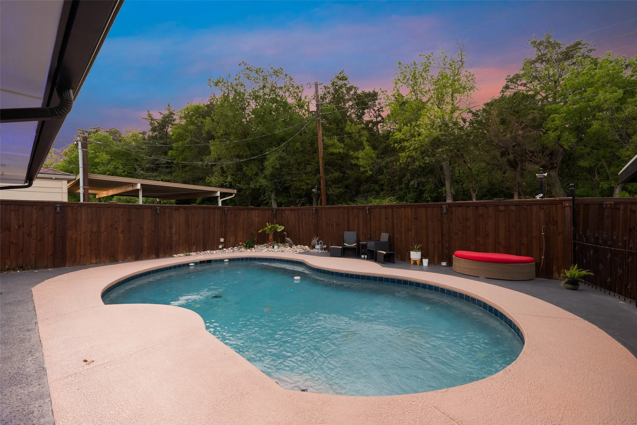 Pool at dusk featuring fence and a patio