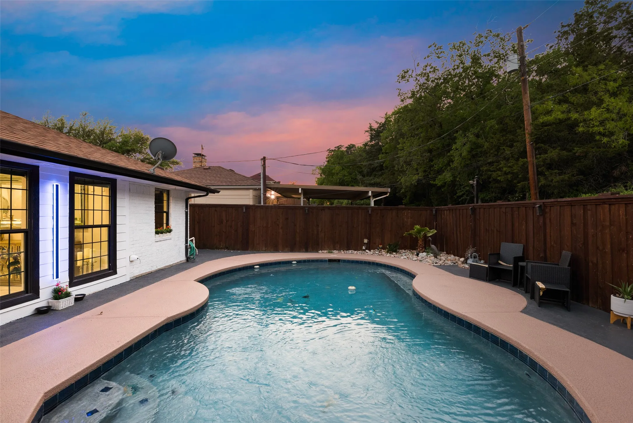 Pool at dusk with a patio area and a fenced backyard