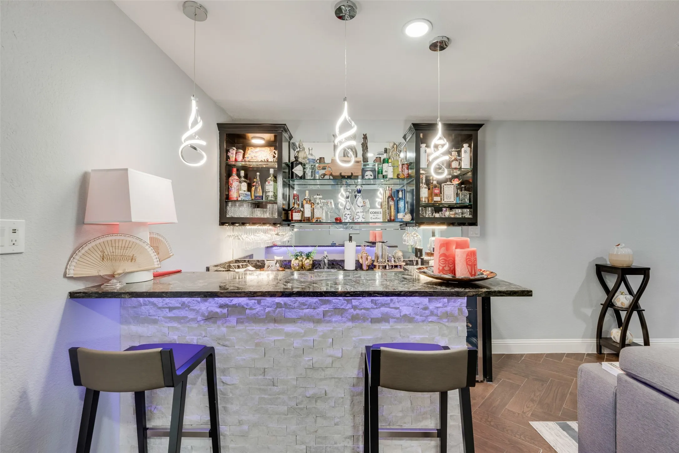 Indoor wet bar featuring hanging light fixtures and baseboards