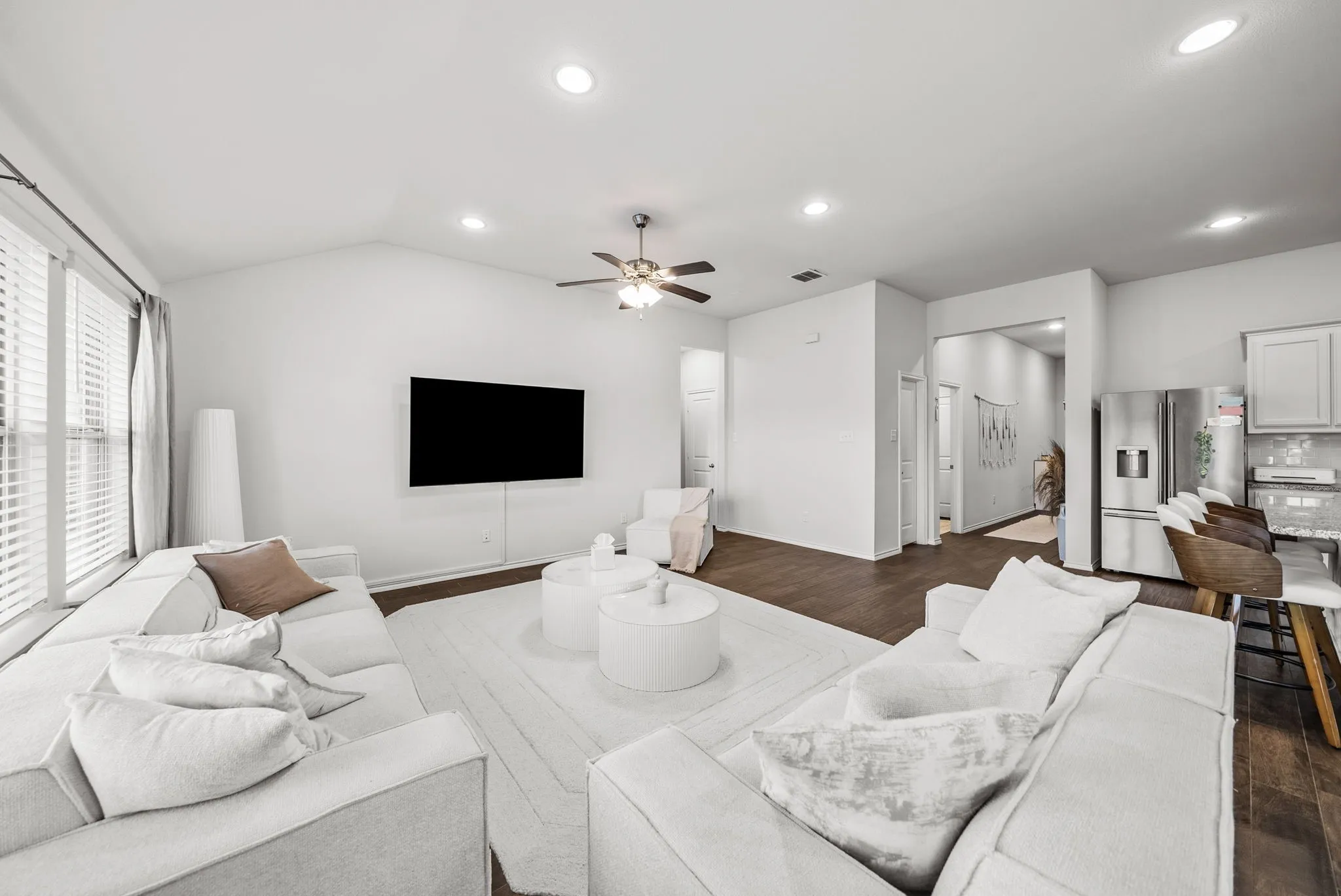 Vaulted ceiling featuring recessed lighting and a ceiling fan, large windows with horizontal blinds, dark wood-finish flooring, and white painted walls