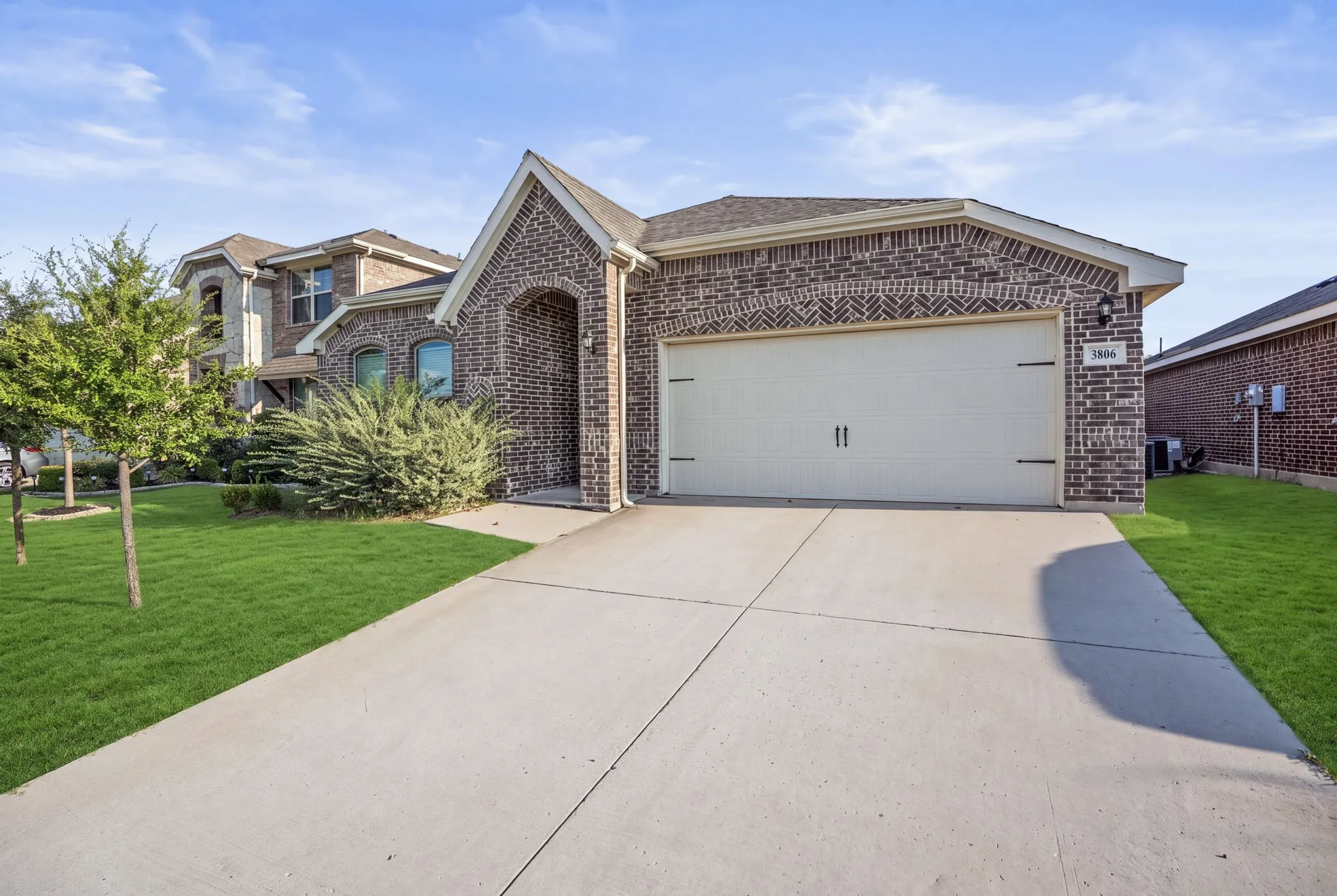 Brick exterior with decorative accents, an arched entry, a two-car garage, and a concrete driveway