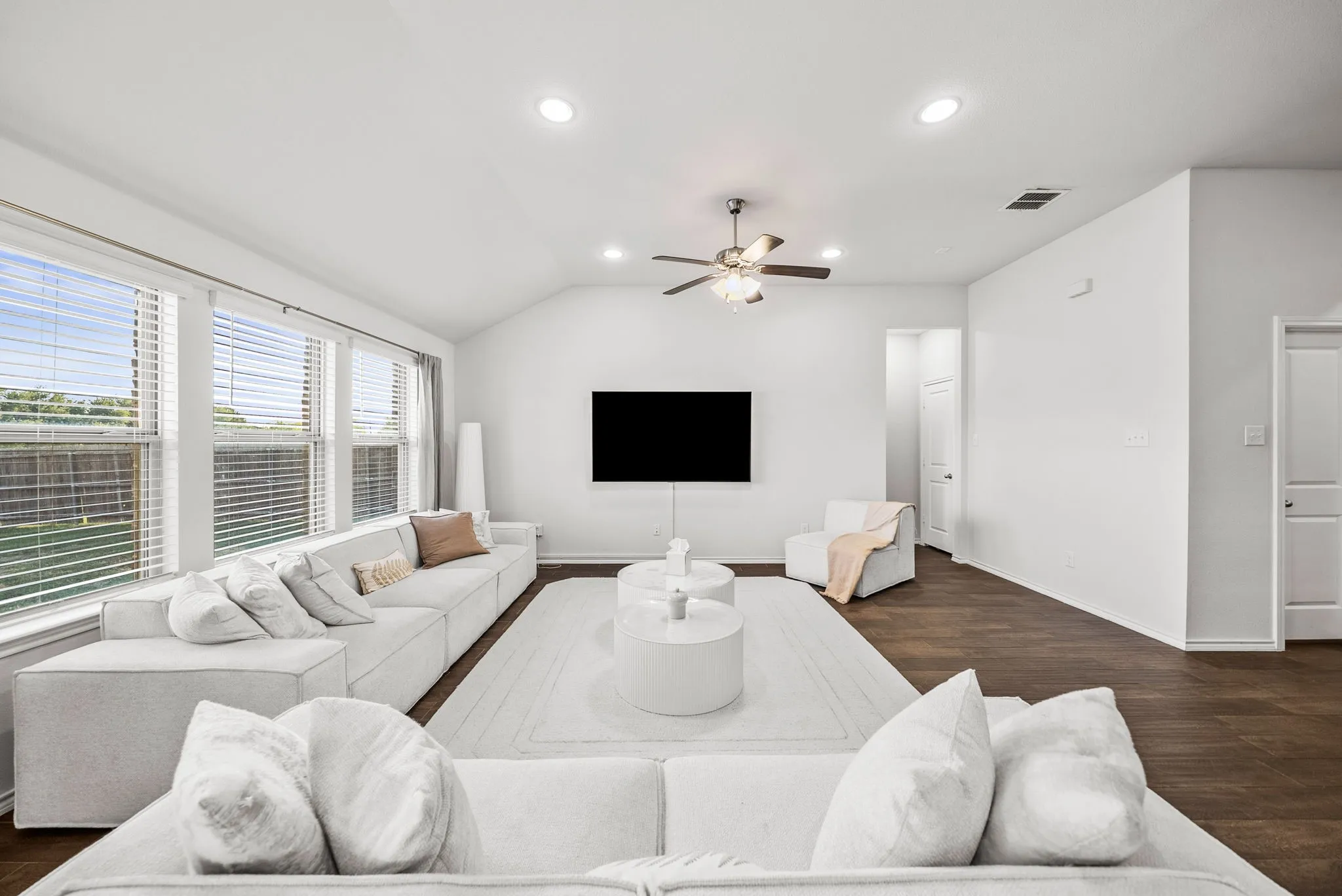 Vaulted ceiling, recessed lighting, ceiling fan, wood-finish flooring, and multiple windows
