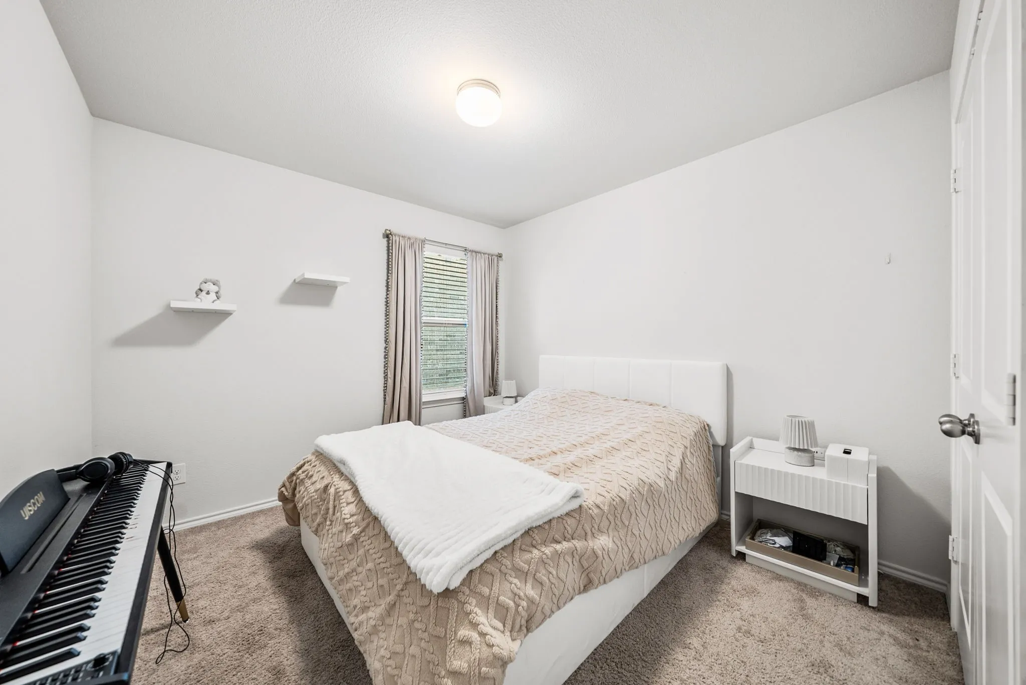 Neutral-toned wall finish, carpet flooring, a window with blinds, and white interior door