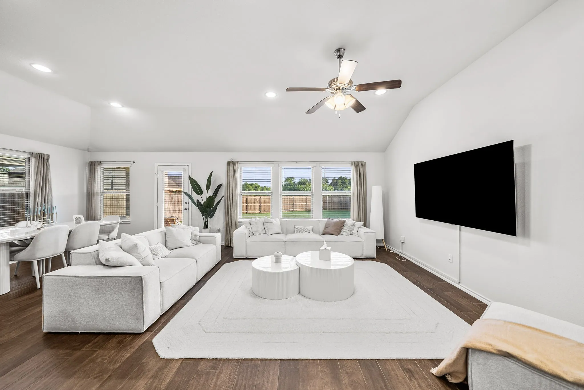 Vaulted ceiling, wood-finish flooring, recessed lighting, ceiling fan, and multiple windows