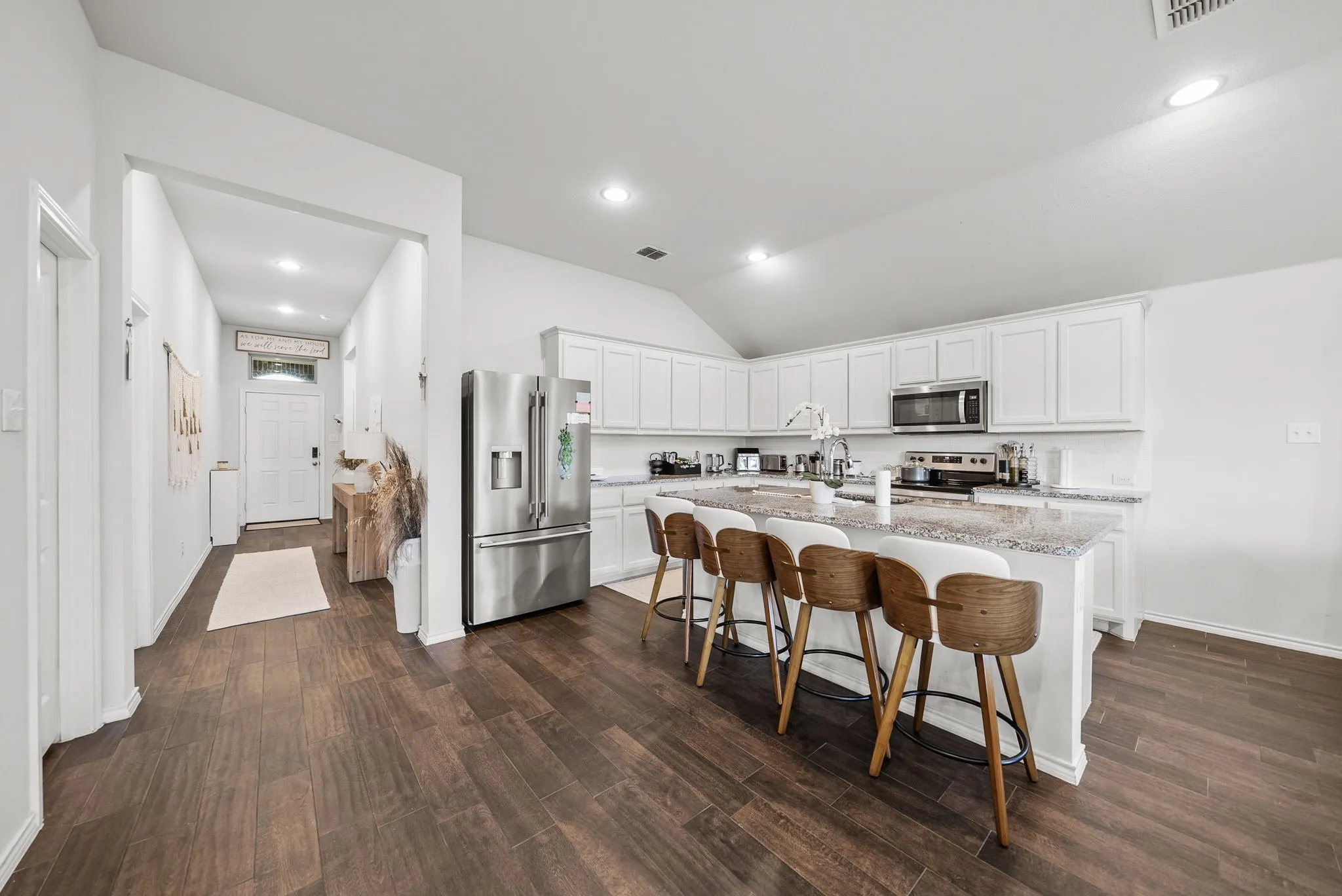 Spacious kitchen featuring white cabinetry, a large island with a speckled countertop, and wood-finish flooring