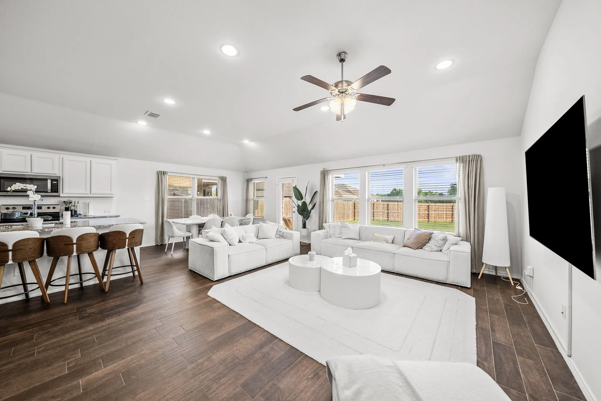 Vaulted ceilings, wood-finish flooring, recessed lighting, and a ceiling fan