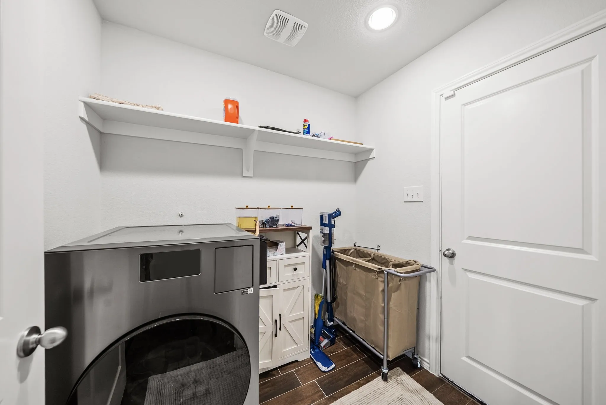 White shelving installed above an appliance space, recessed ceiling light, and wood-finish flooring