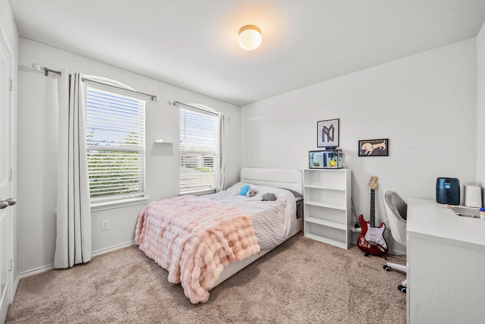 Bright room featuring two windows with blinds, neutral carpeting, a built-in ceiling light fixture, and white painted walls