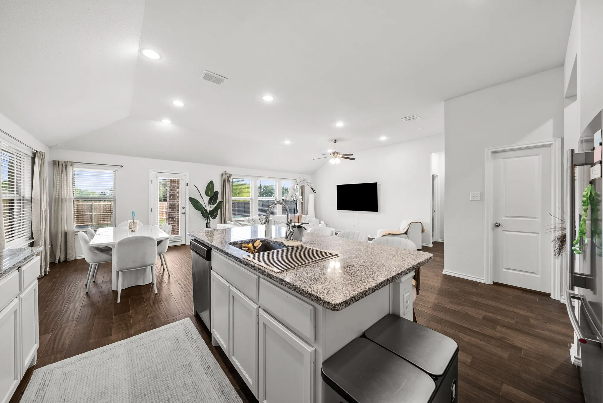 Kitchen island with granite countertops, wood-finish flooring, recessed lighting, and a vaulted ceiling