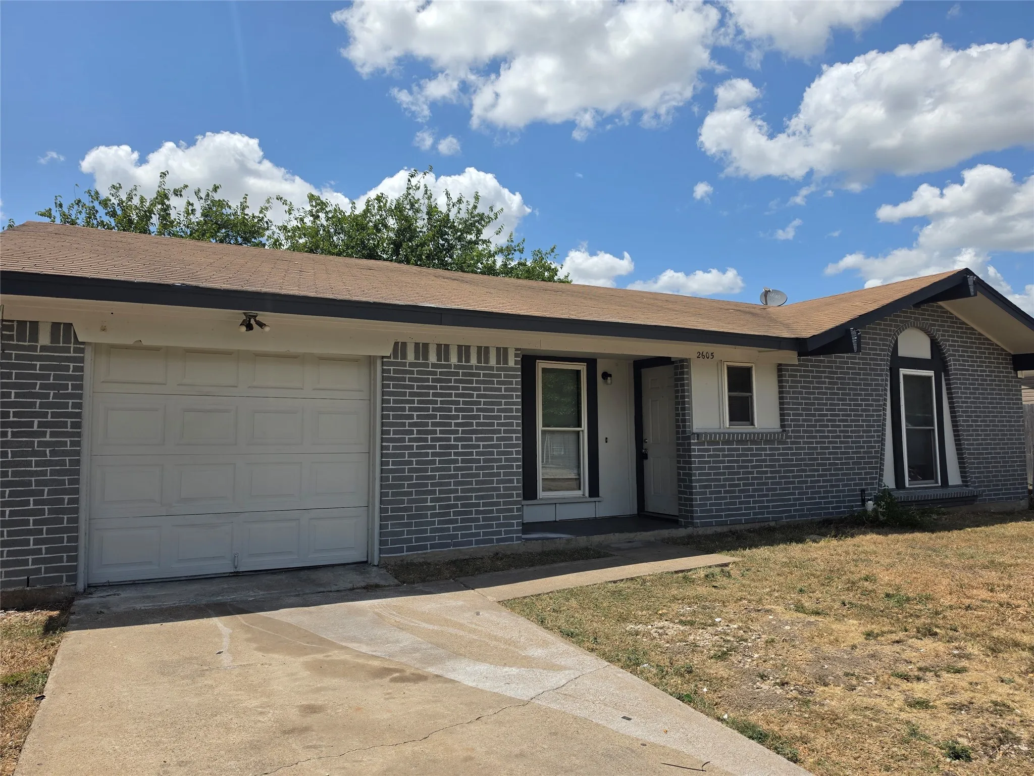 Gray brick exterior with a tan shingle roof
