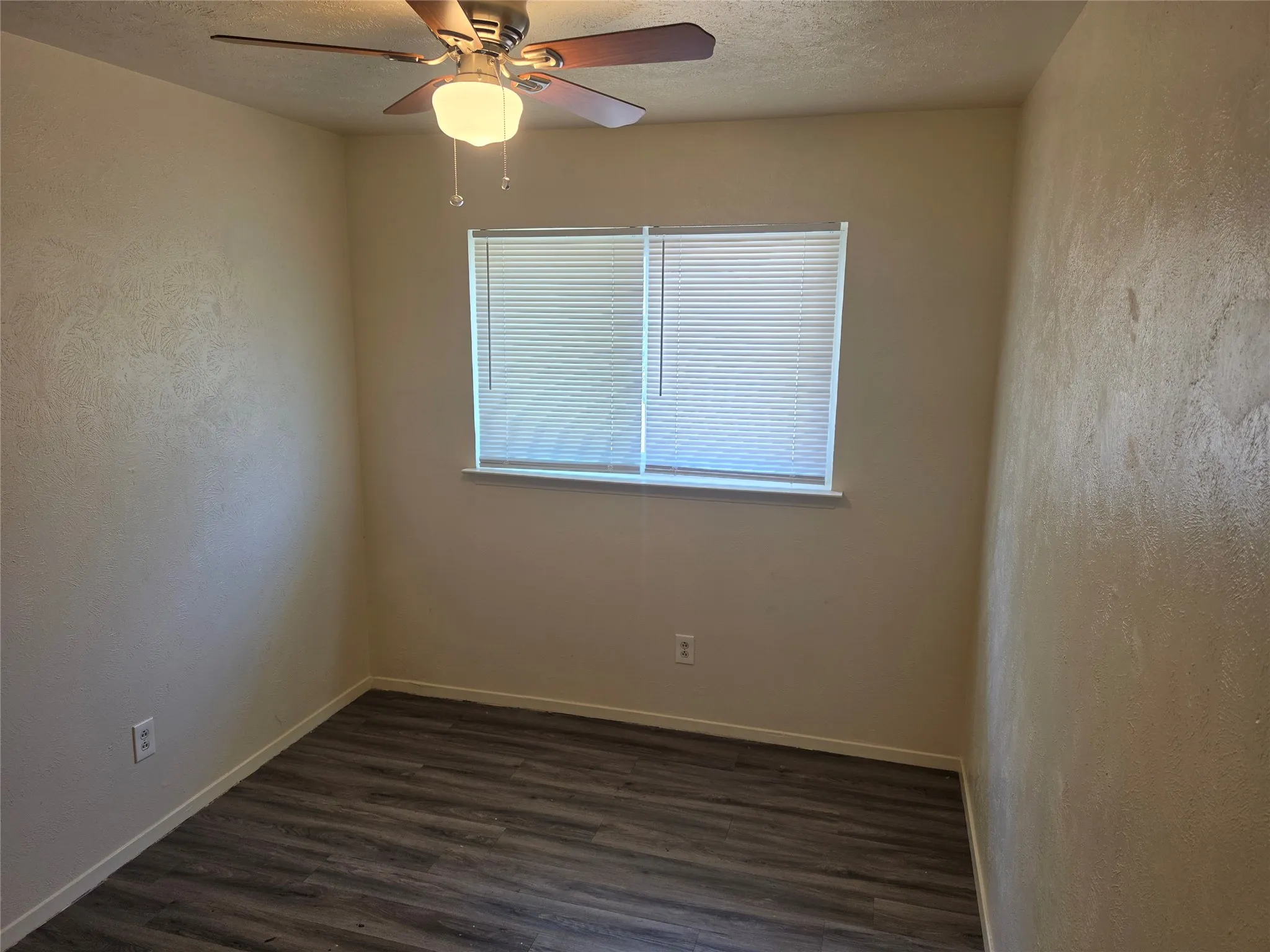 Wood-finish flooring, window with blinds, and a ceiling fan with integrated lighting