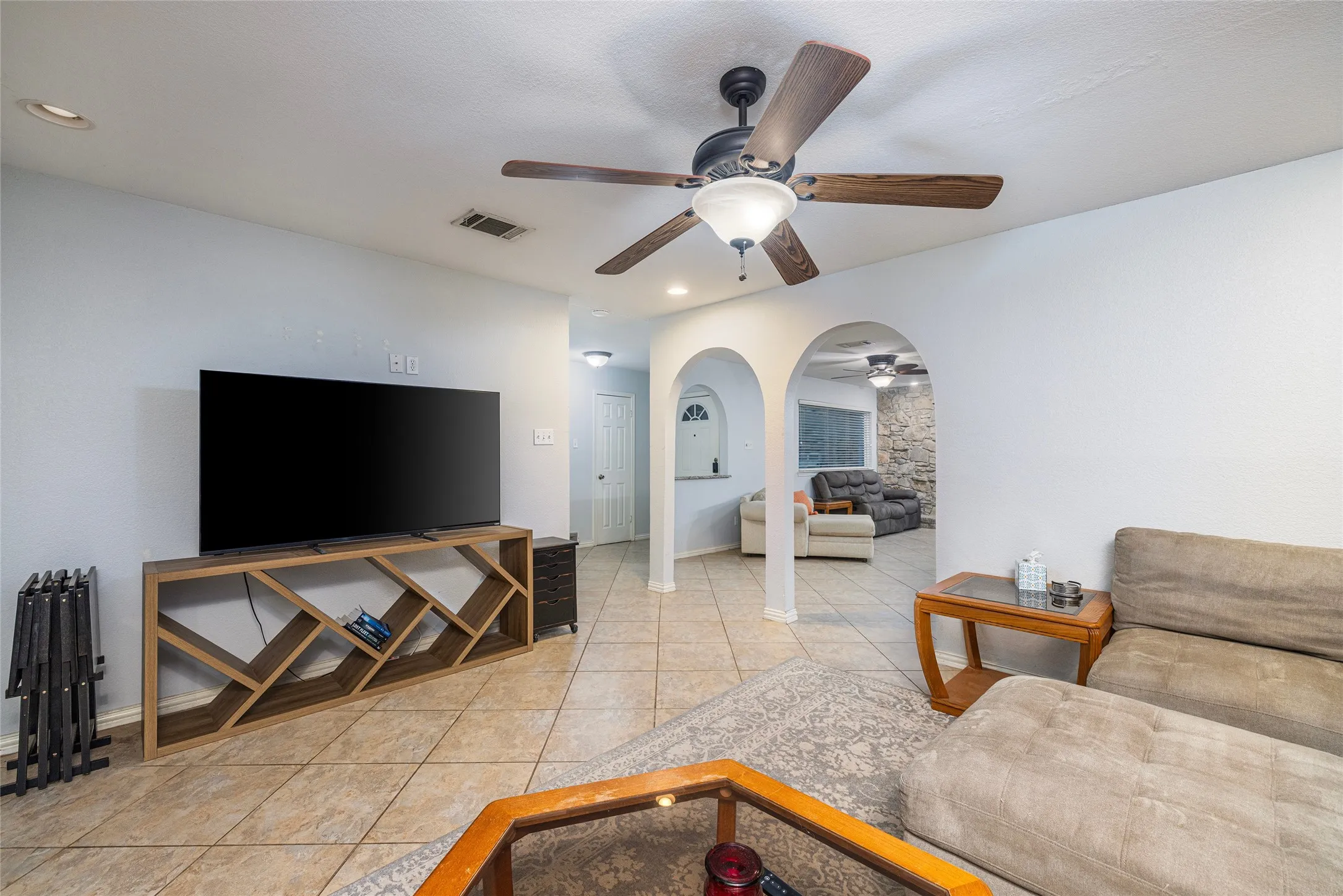 Ceiling fan with light fixture, recessed lighting, tile flooring, and arched doorways