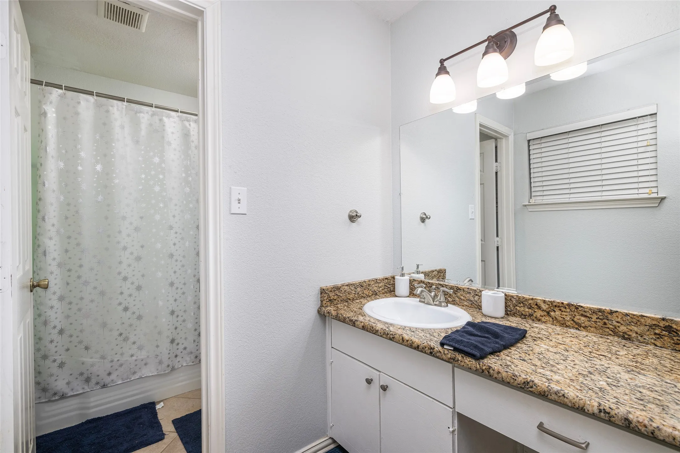 Vanity with a polished stone countertop, undermount sink, and brushed nickel faucet