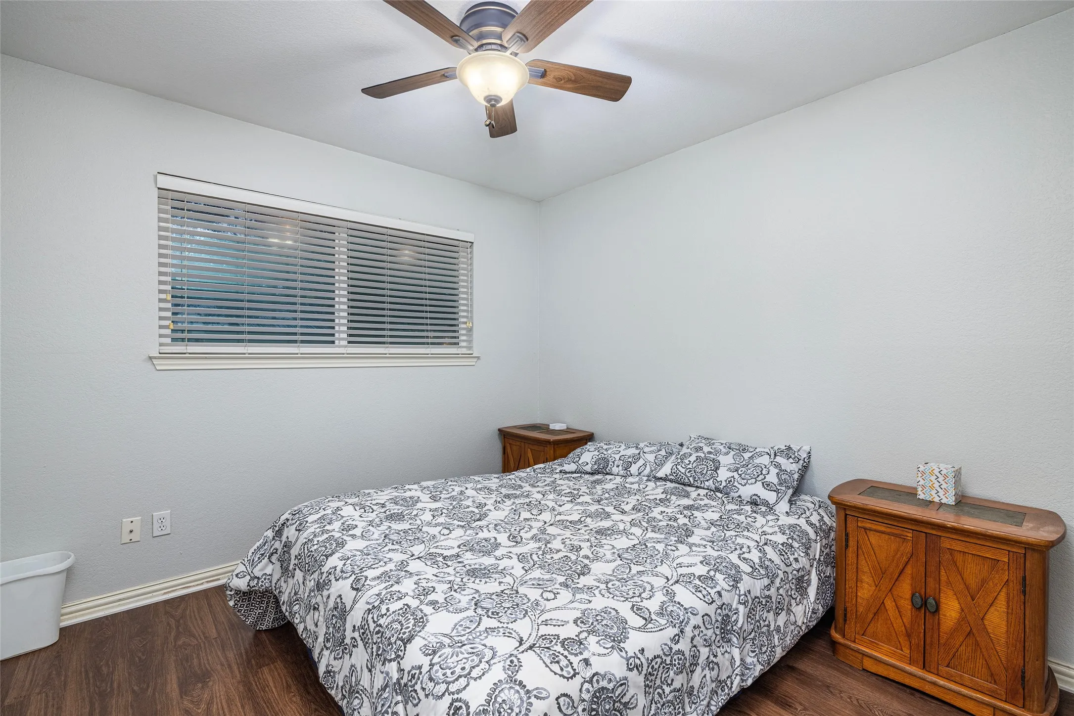 Wood-finish flooring with a ceiling fan and overhead lighting