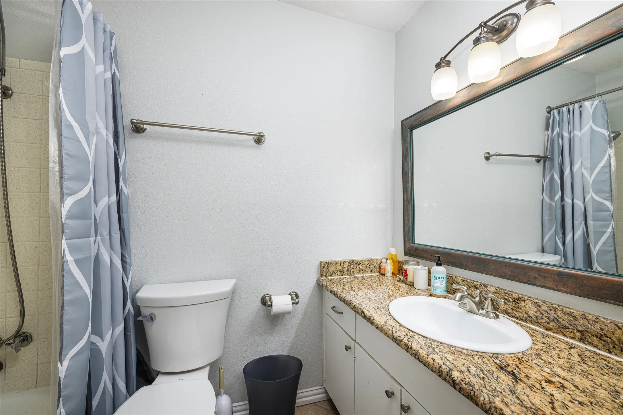 Vanity featuring a stone countertop, an undermount sink, and a framed mirror with an overhead light fixture