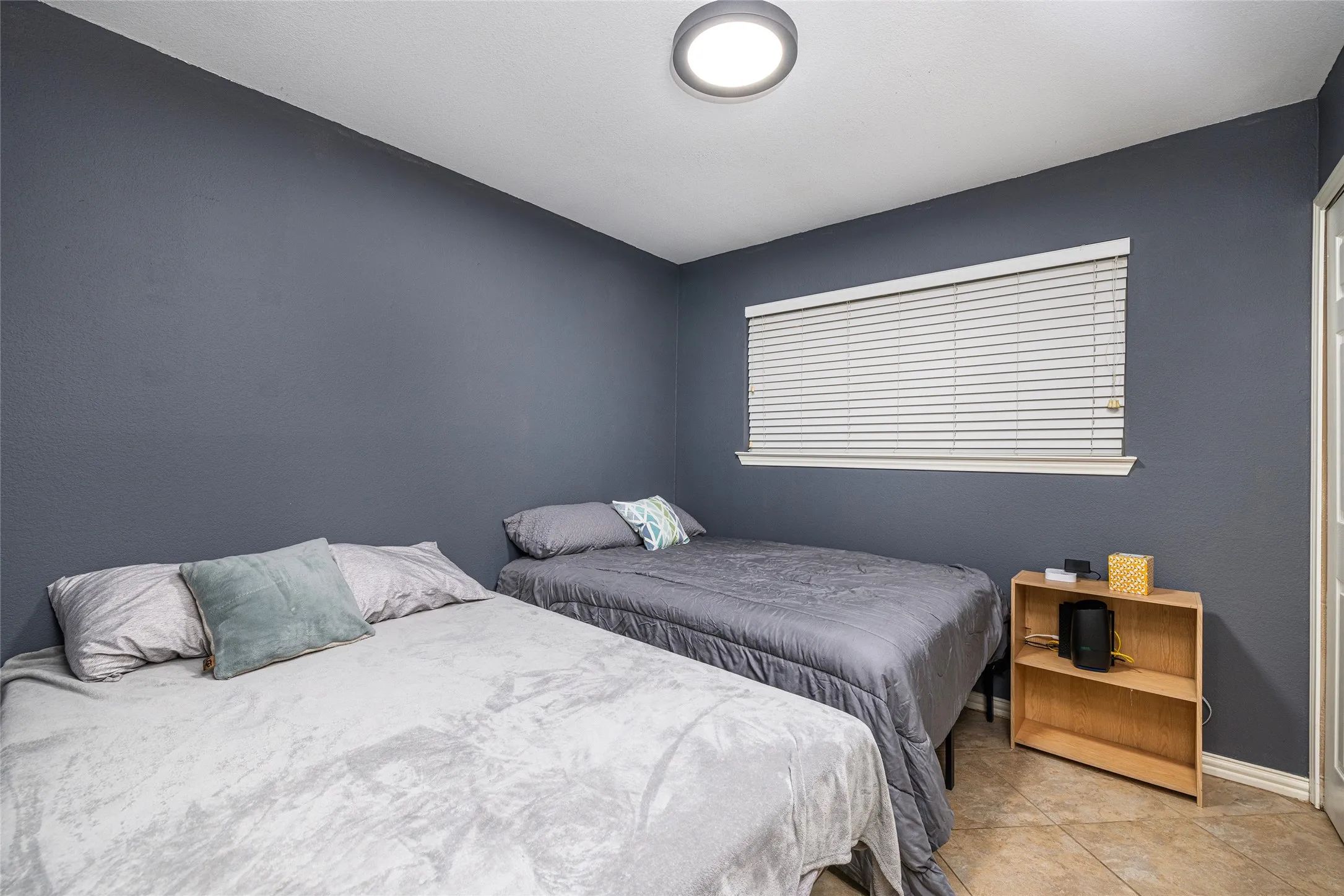 Room featuring solid wall color, window with horizontal blinds, and a flush-mount ceiling light fixture