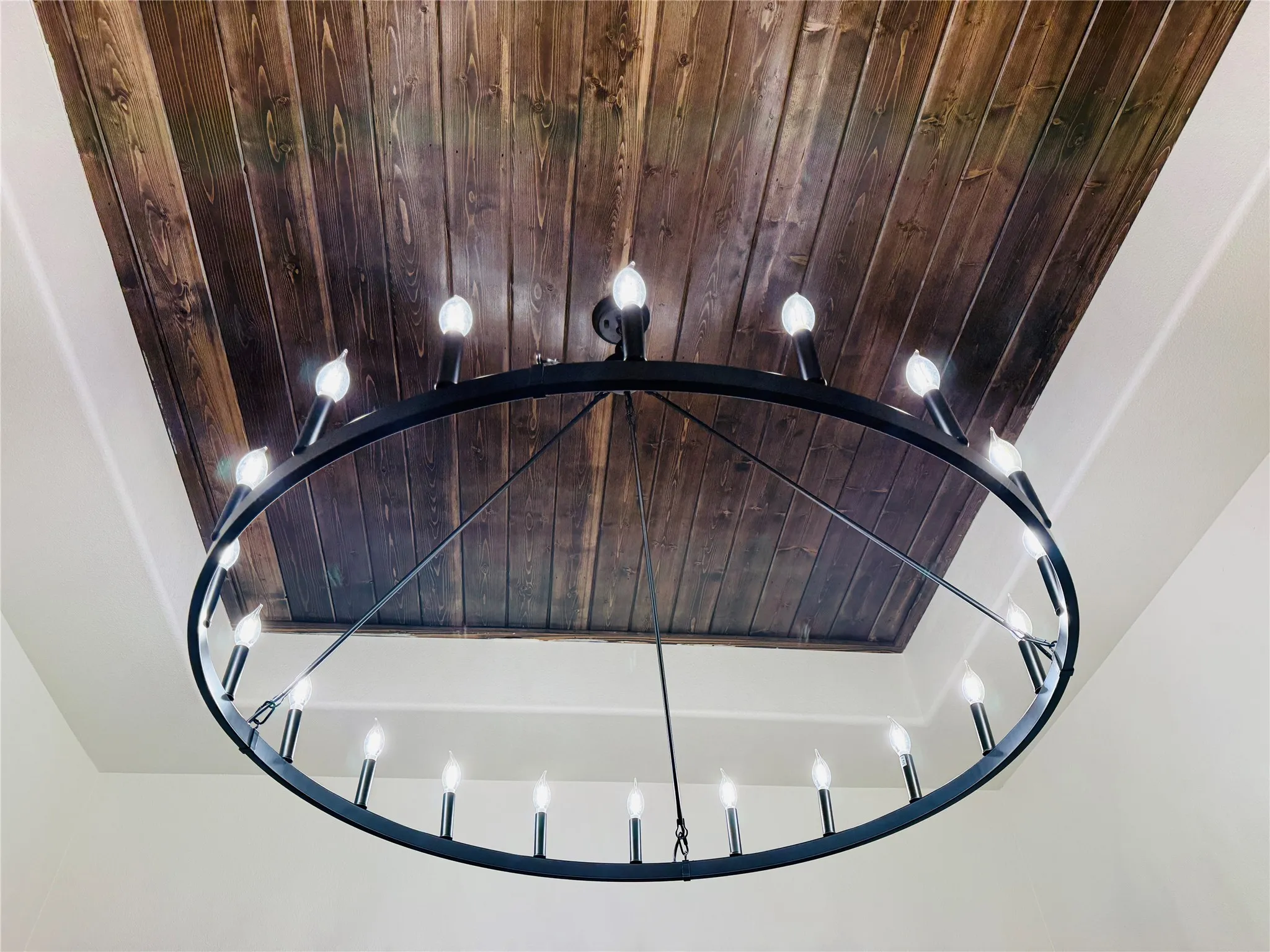 Built-in wood ceiling with a large circular chandelier featuring multiple candelabra bulbs
