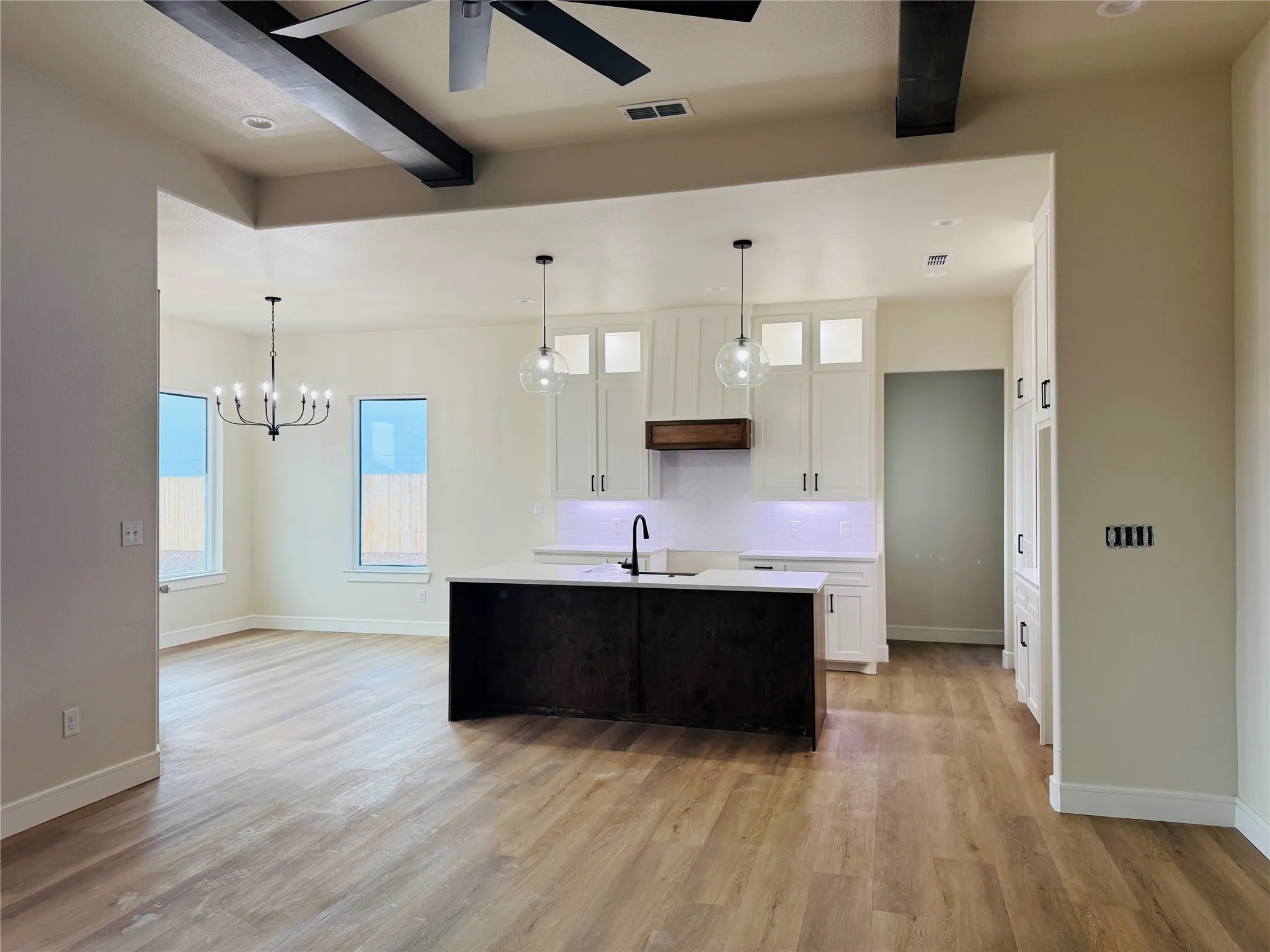 Open-concept kitchen with a central island, white cabinetry, and pendant lighting