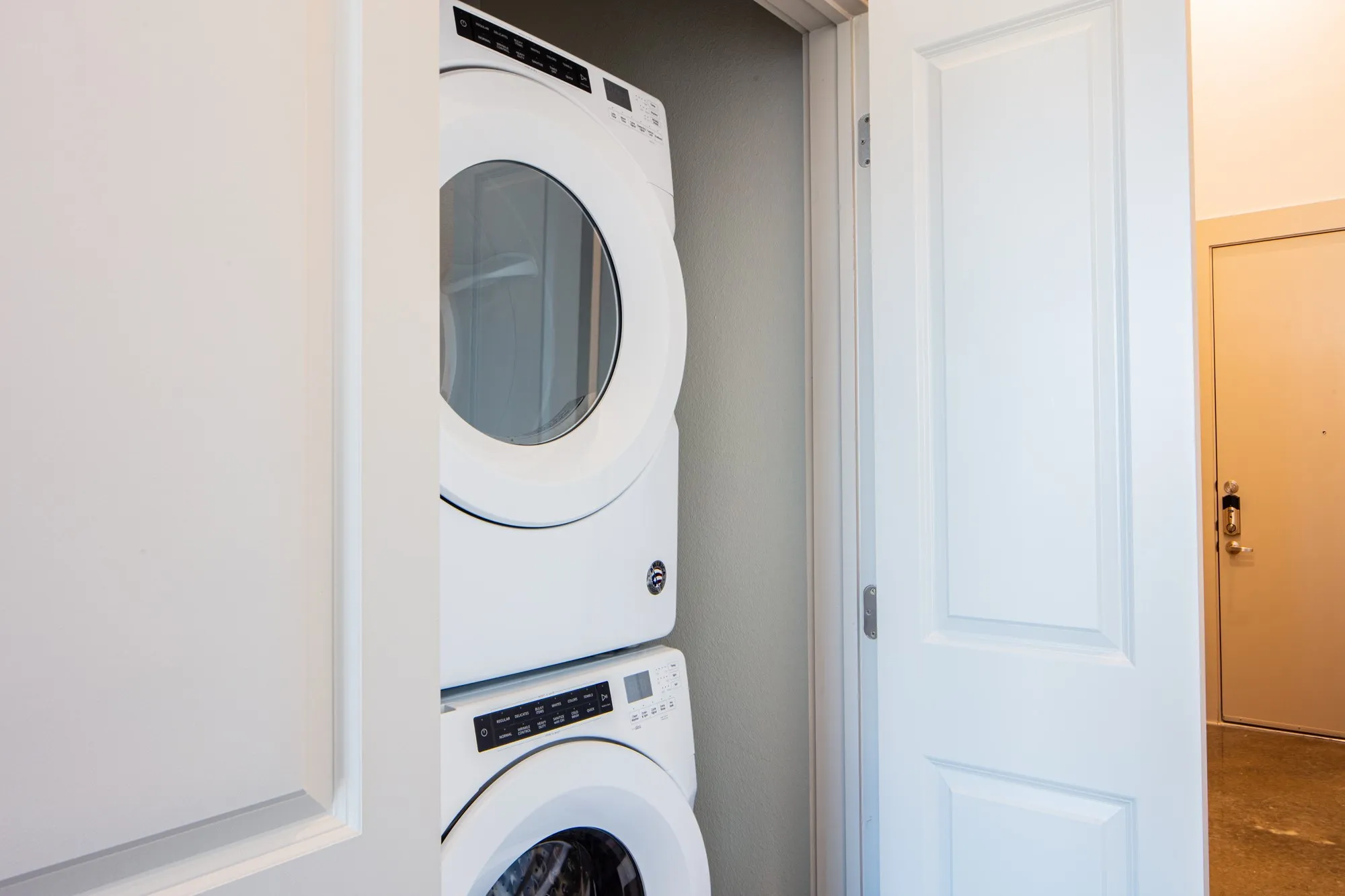 Clothes washing area featuring stacked washing maching and dryer