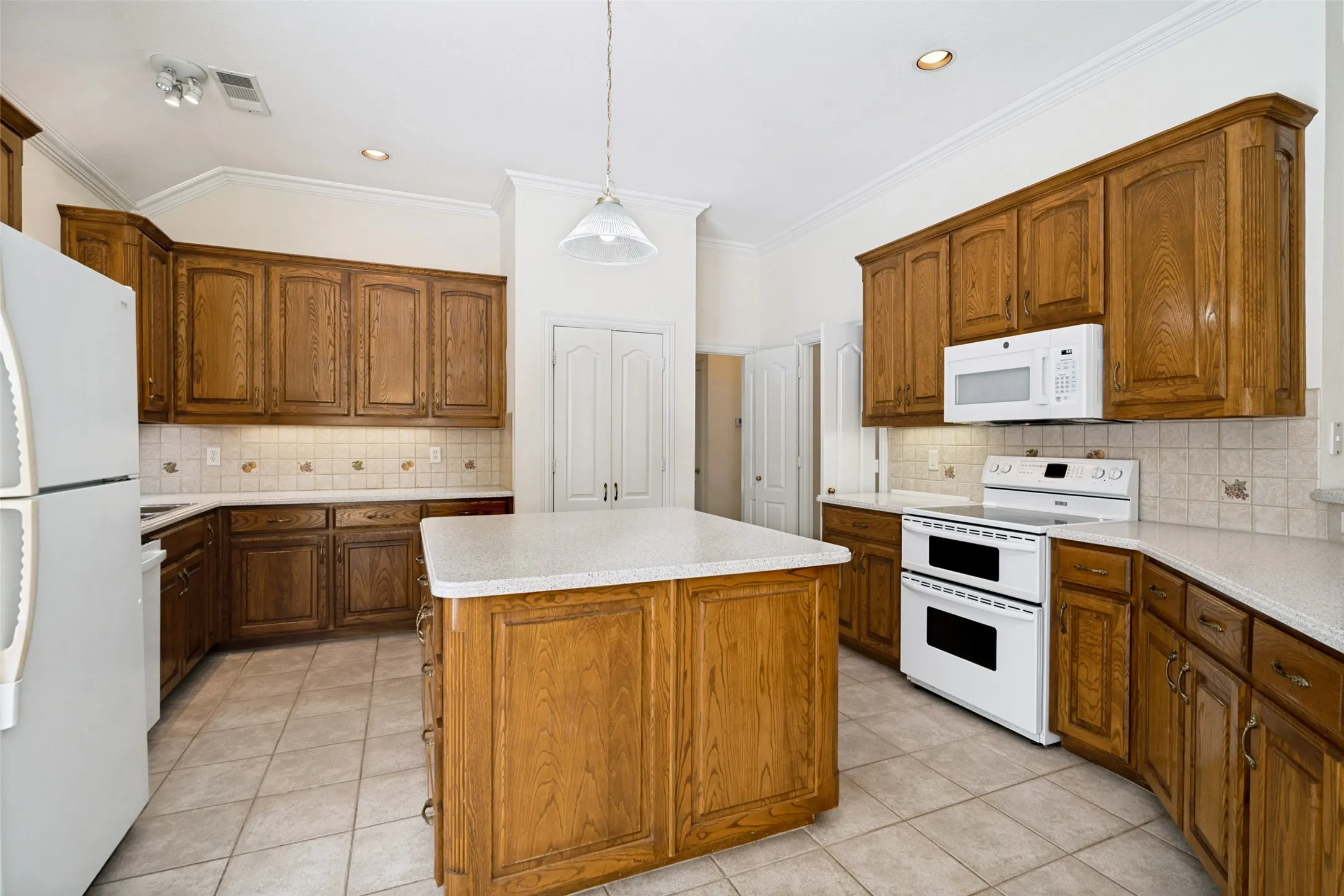 Gourmet custom kitchen has 42 inch oak cabinets, corian countertops, a large island and decorative tile backsplash.