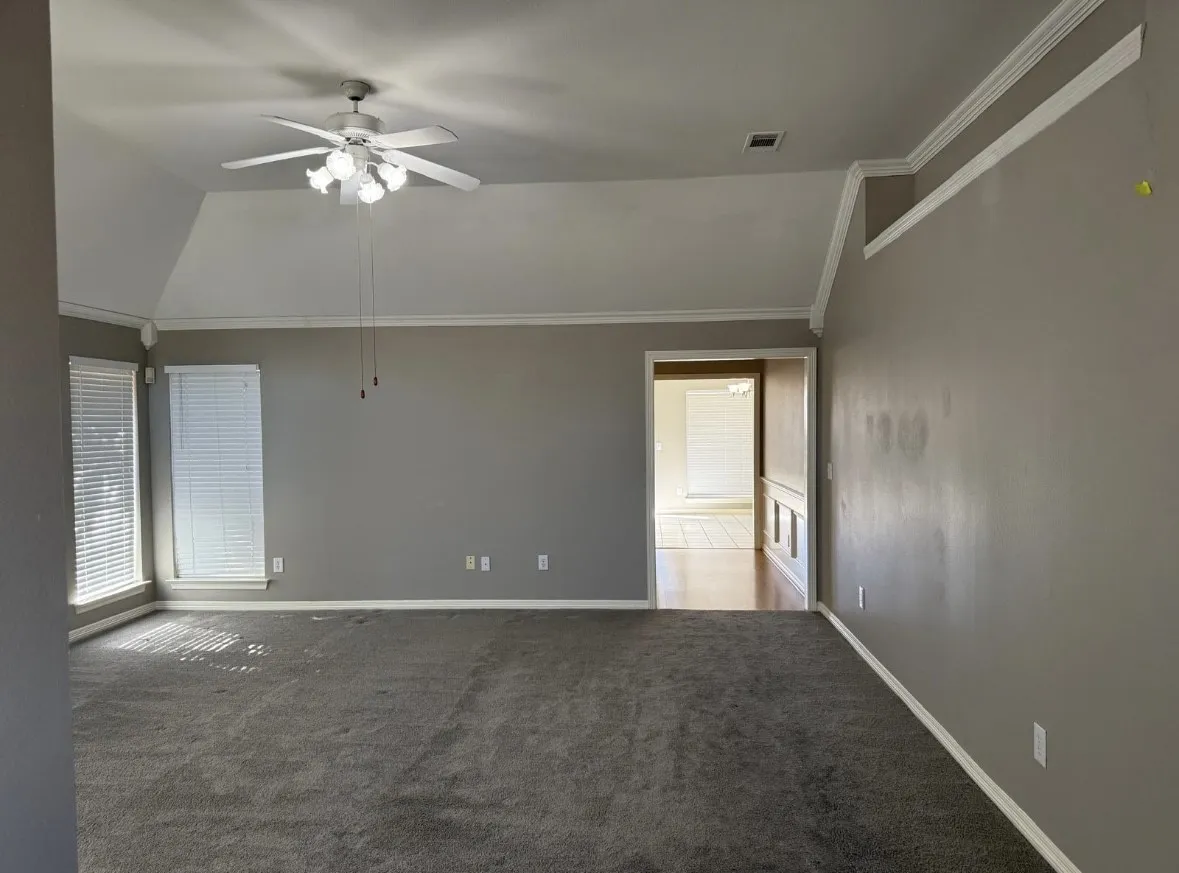 Unfurnished room with lofted ceiling, crown molding, ceiling fan, and carpet