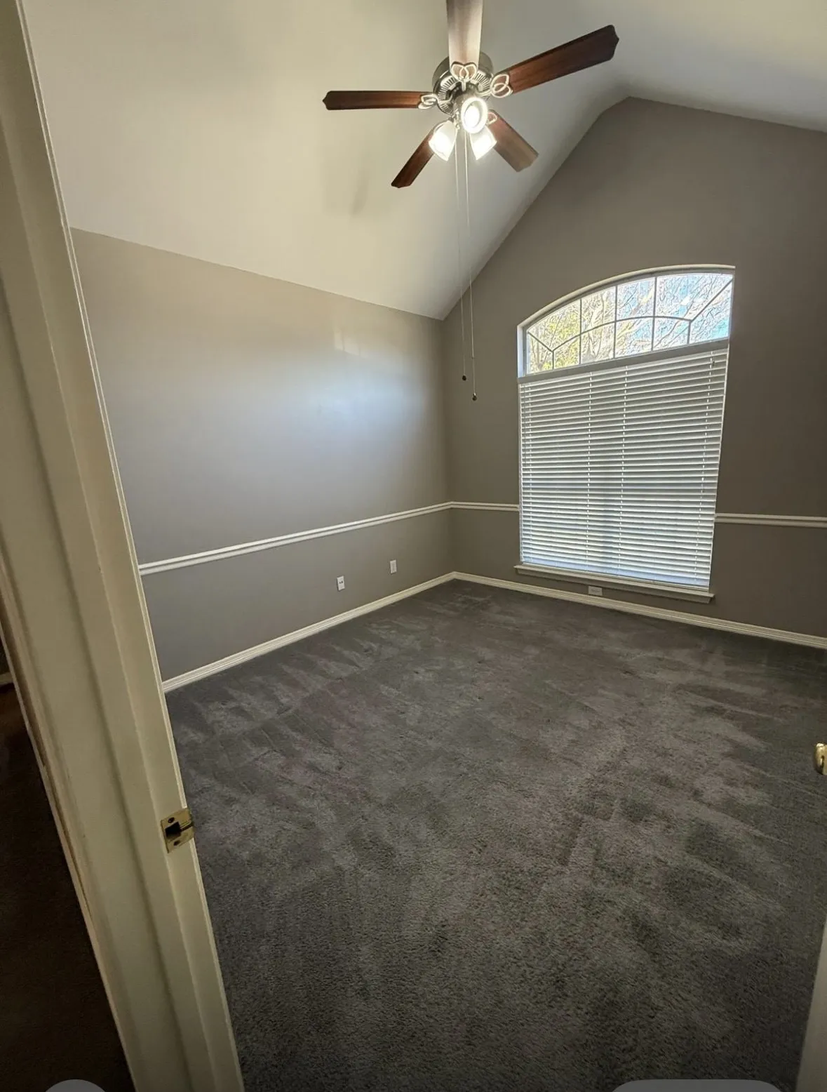 Spare room featuring lofted ceiling, dark carpet, and ceiling fan