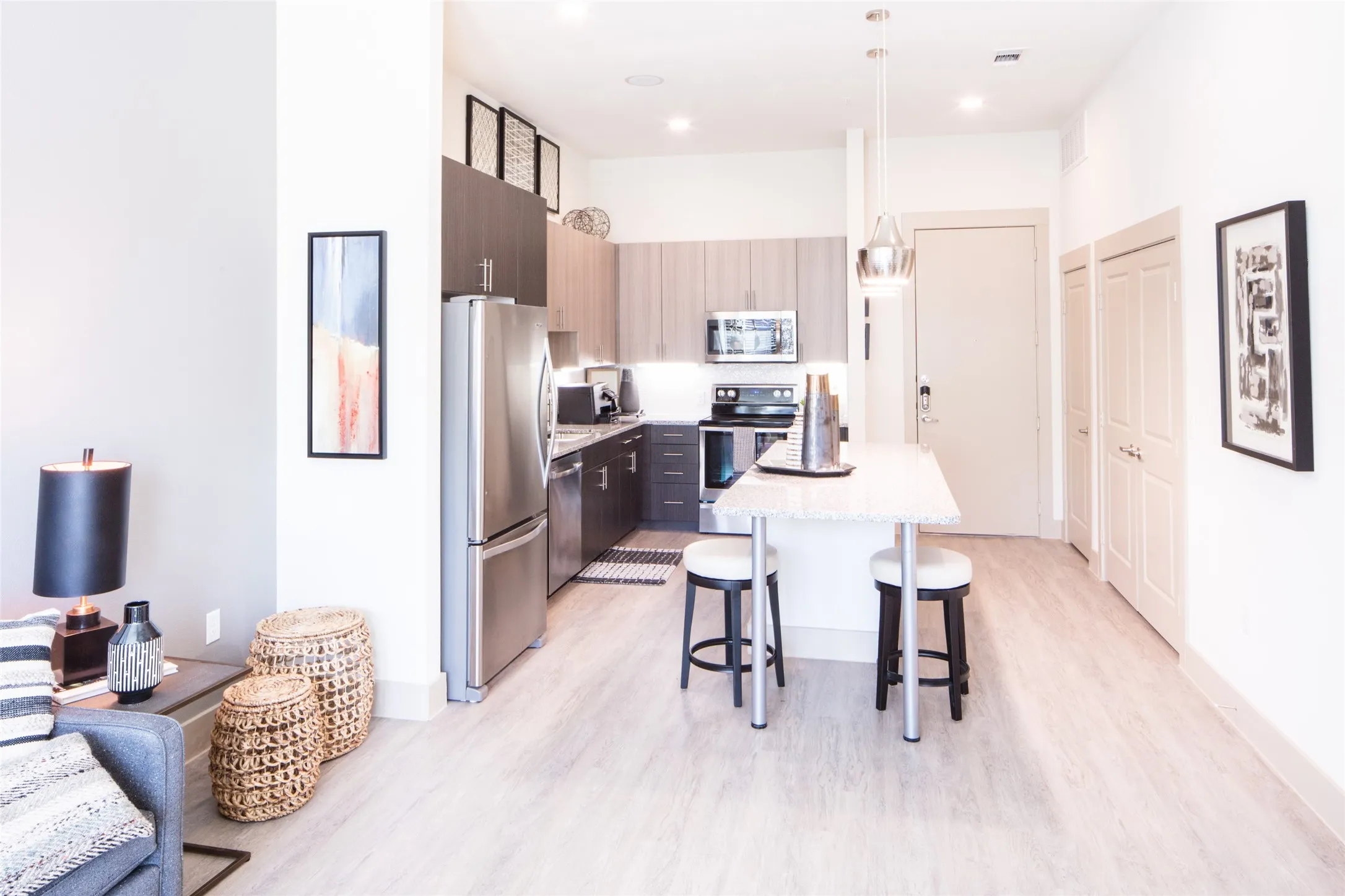 Kitchen featuring a breakfast bar, decorative light fixtures, light hardwood / wood-style flooring, appliances with stainless steel finishes, and a center island