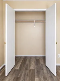 Closet with wood-finish flooring, white bifold doors, and a clothing rod