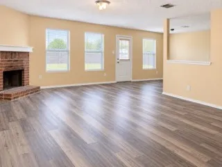 Wood-finish flooring throughout, brick fireplace with mantel, multiple windows with blinds, and recessed lighting