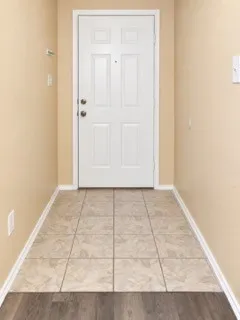 Entryway with tiled flooring, contrasting wood-finish flooring, and a paneled entry door