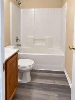 White bathtub and shower combination with a bright chrome shower head and fixtures
