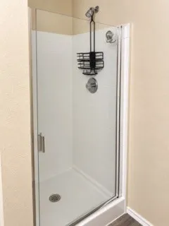 Walk-in shower with clear glass enclosure, white subway tile surround, and a chrome shower fixture