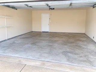 Spacious garage with light-toned walls, a durable concrete floor, and built-in shelving