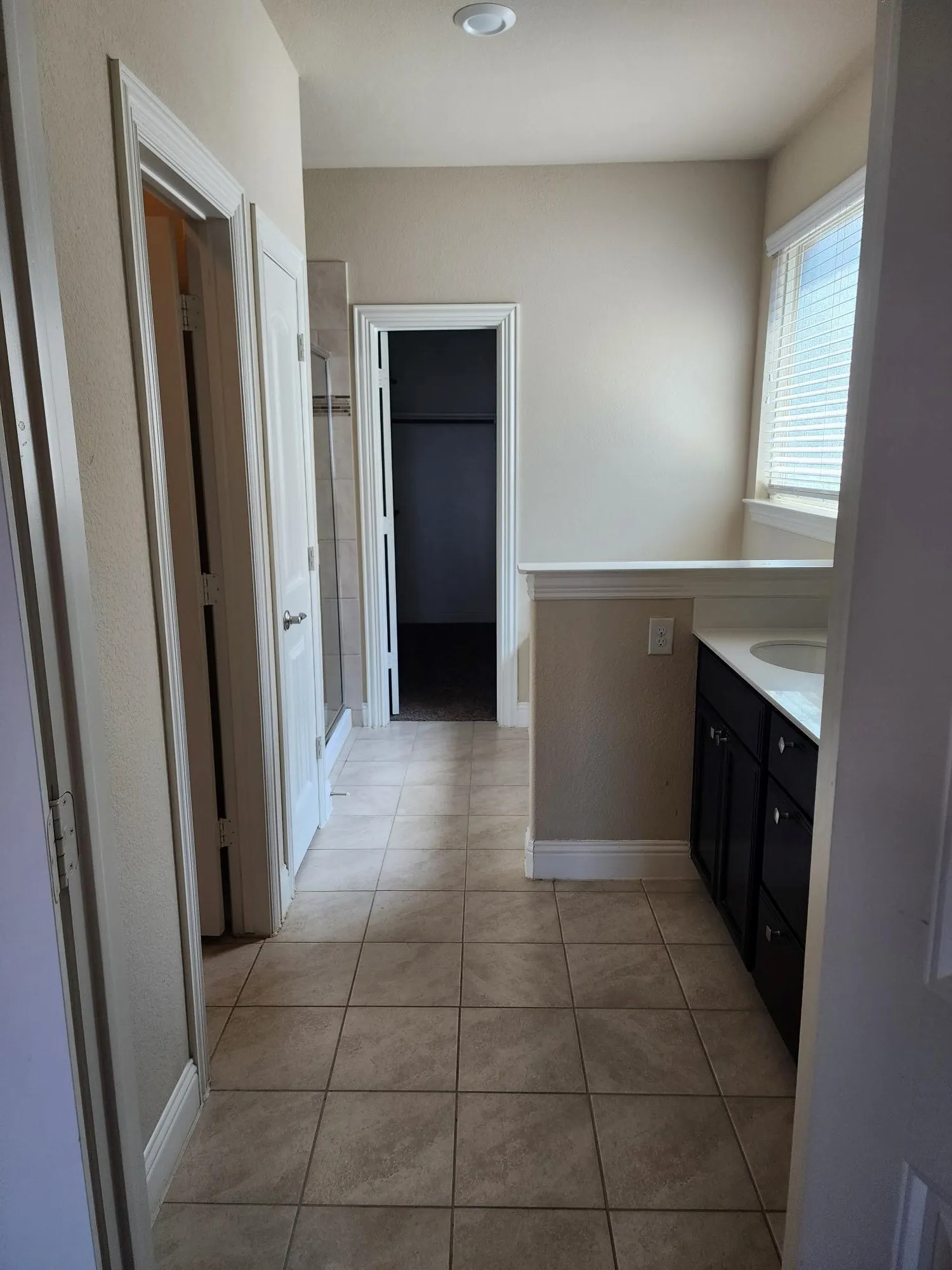 Recessed ceiling lighting, tiled flooring, built-in vanity with dual sinks, window with blinds, and a shower enclosure