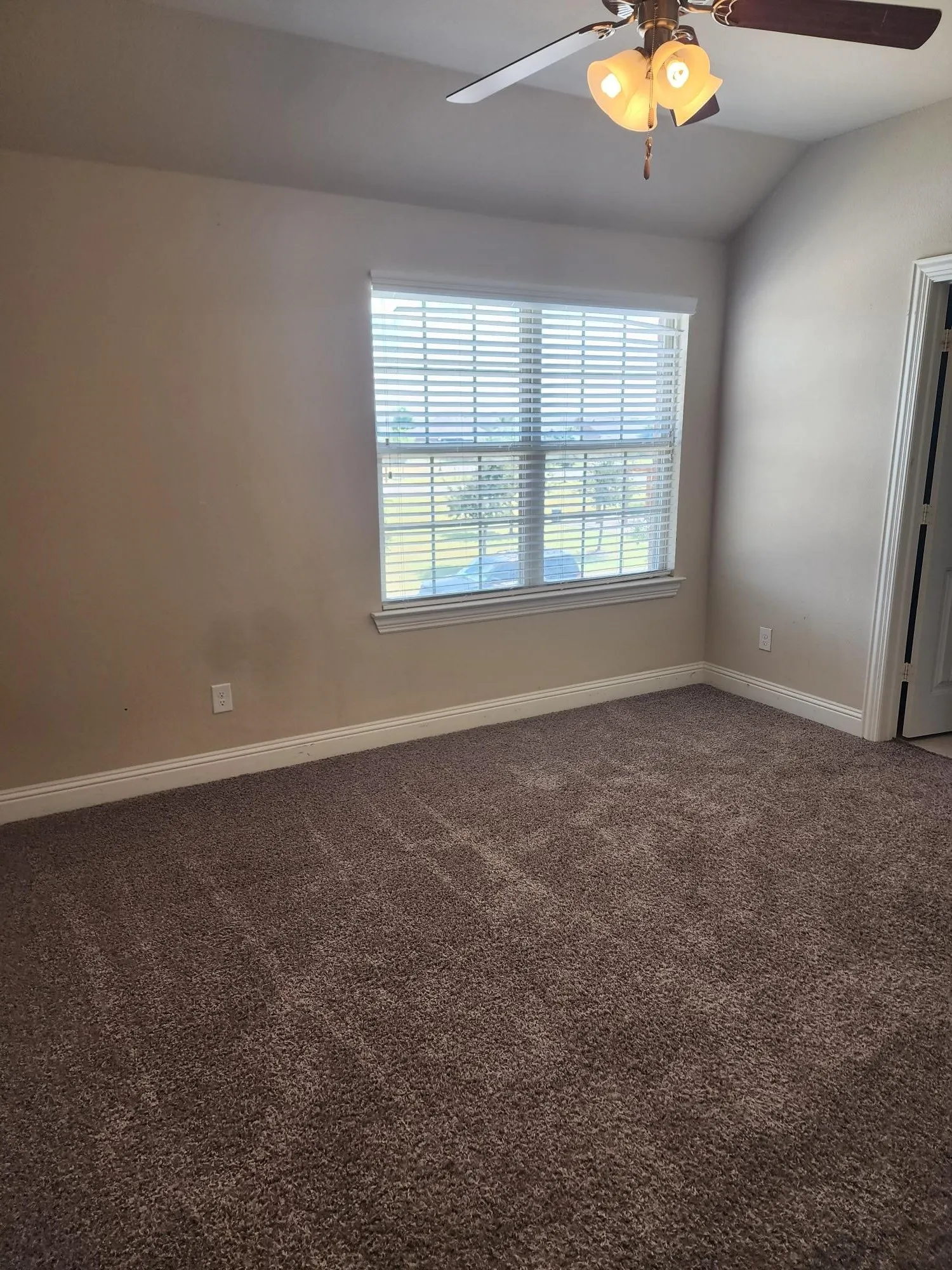 Vaulted ceiling with a ceiling fan, window with blinds, and wall-to-wall carpeting