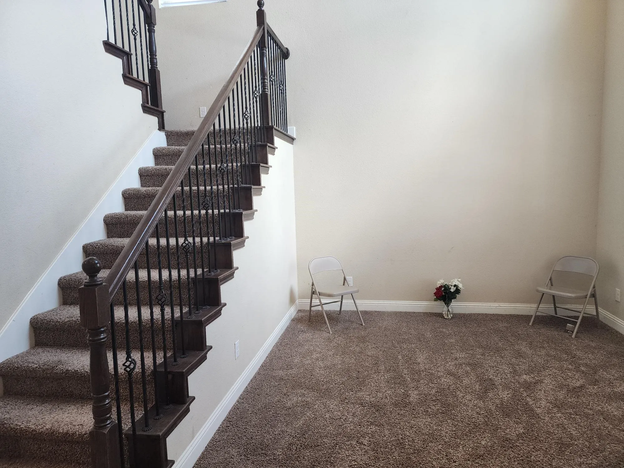 Carpeted staircase featuring wood newel posts and handrails with wrought iron balusters