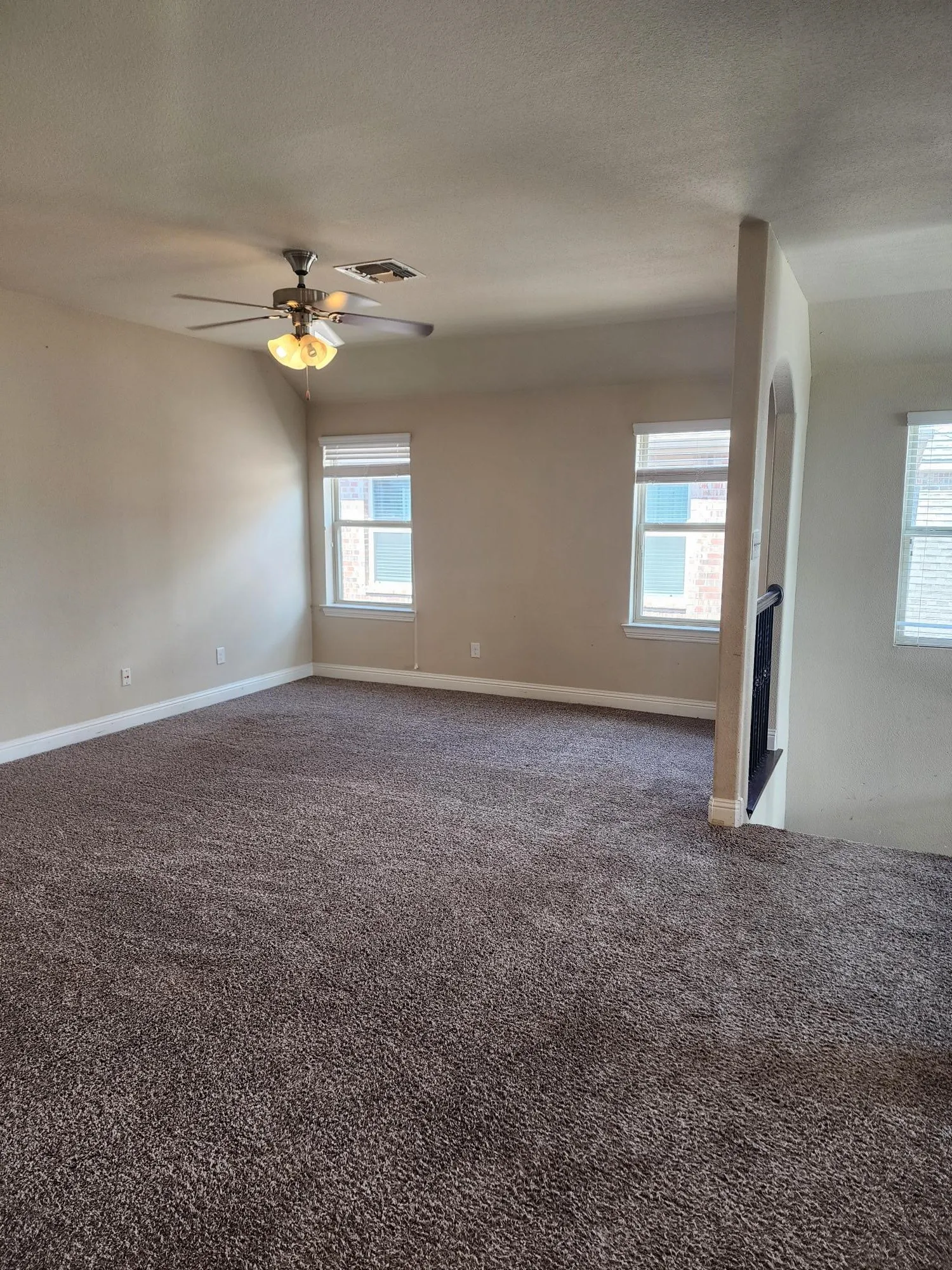 Carpeted living area featuring multiple windows, a ceiling fan with integrated lighting, and a built-in fireplace