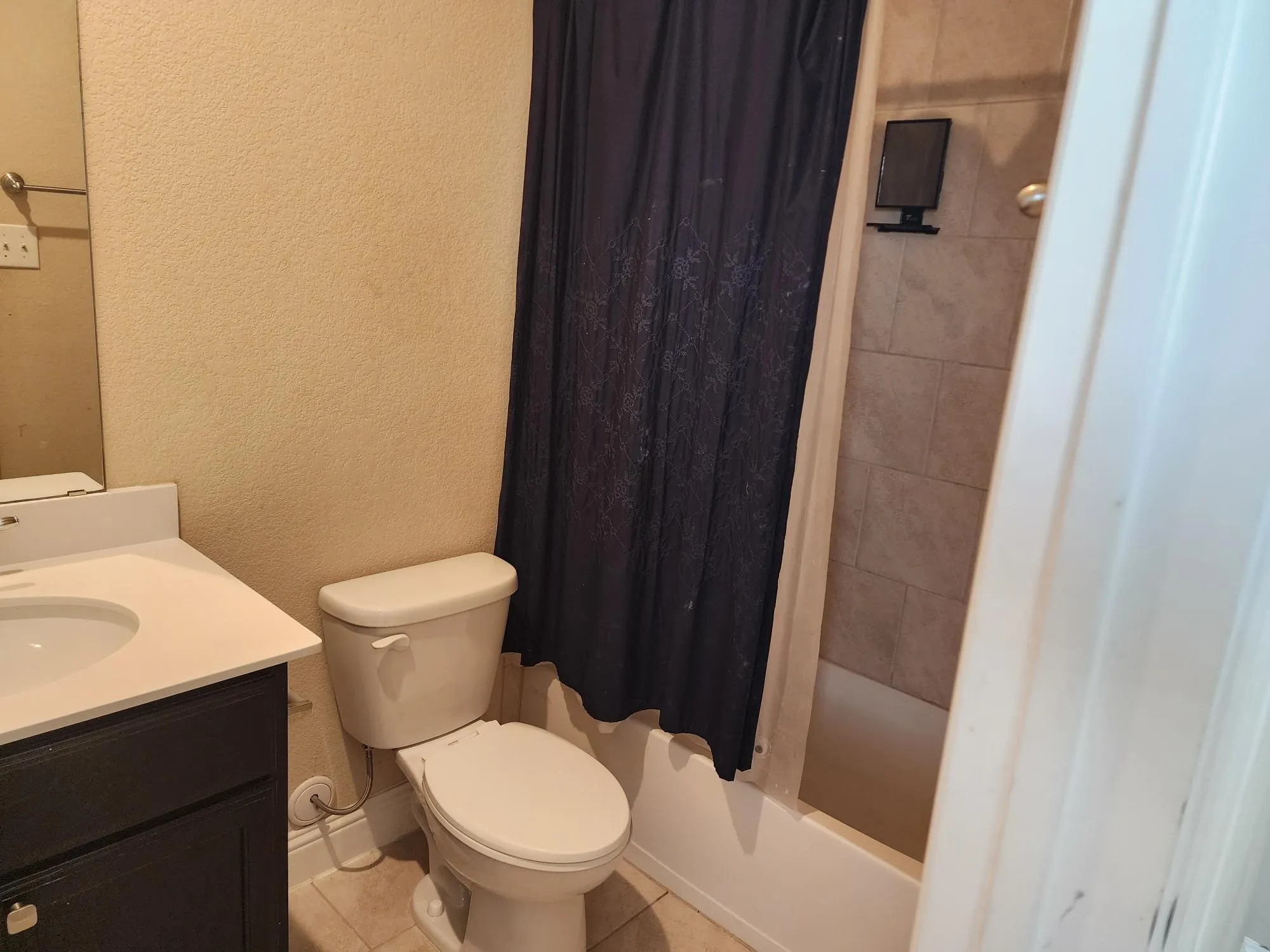 Bathroom featuring a white vanity with an integrated sink, dark wood-finish cabinetry, a standard toilet, and a tiled shower/tub combination