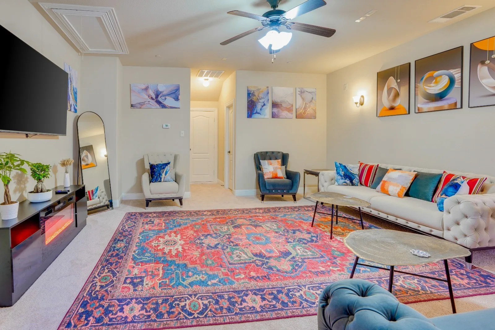 Recessed ceiling feature, ceiling fan with integrated lighting, wall-mounted television, built-in entertainment console with electric fireplace, and wall sconces