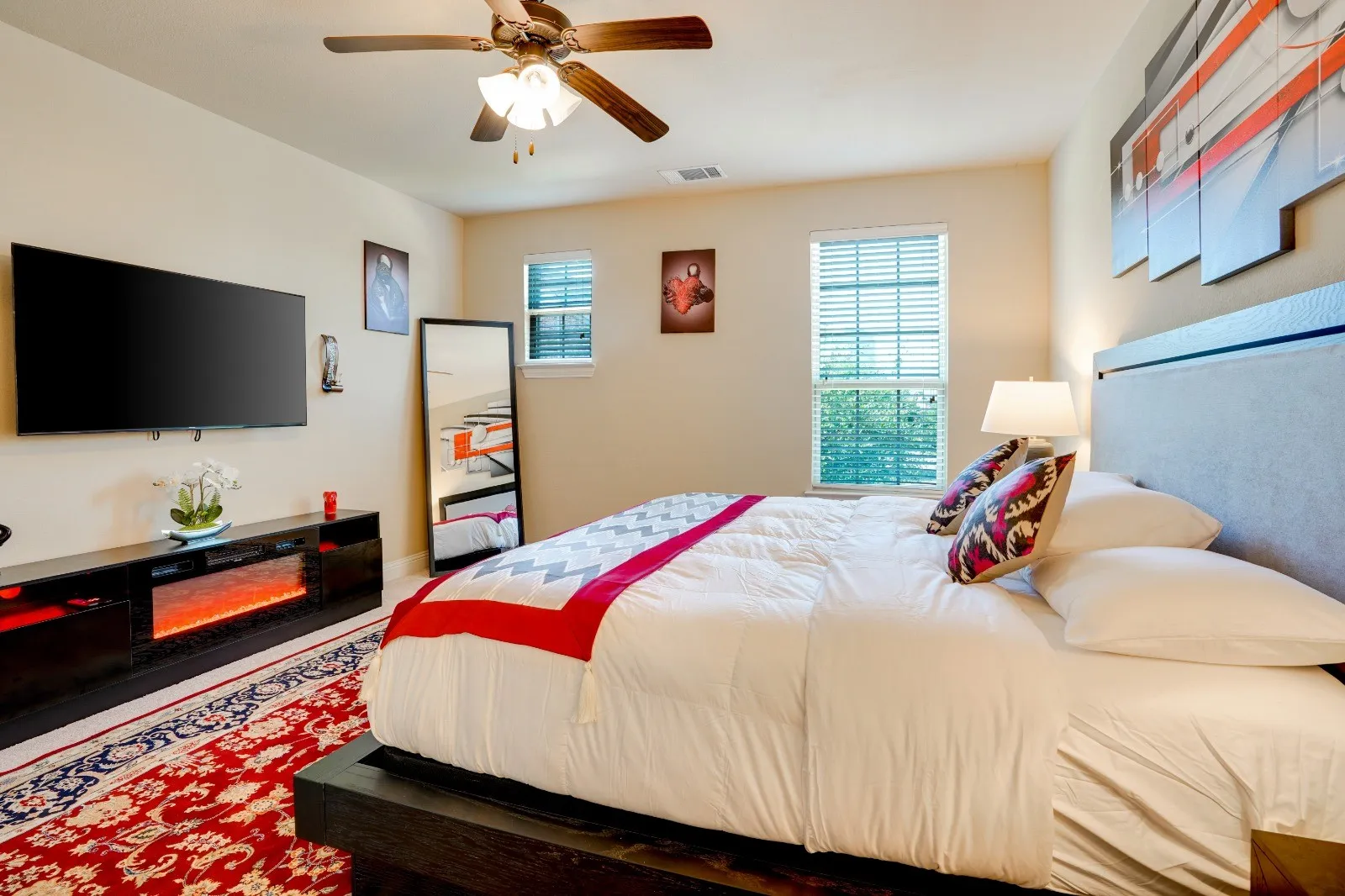 Recessed lighting, wood-finish ceiling fan, window with blinds, built-in media console with fireplace feature, and a substantial upholstered headboard
