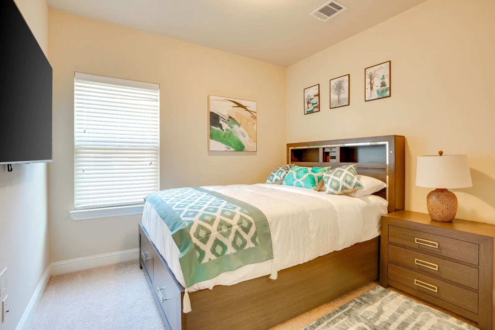 Window with blinds, wall-mounted television, and neutral-toned carpeting