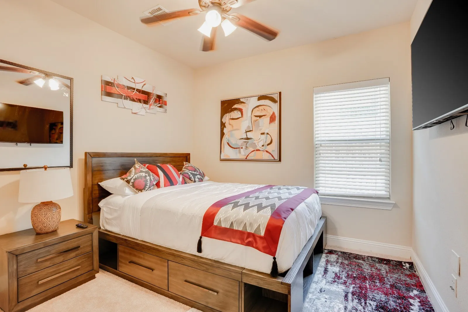 Wood-finish bed frame with built-in storage drawers, a coordinating wood-finish nightstand, a ceiling fan with integrated lighting, and a window featuring blinds
