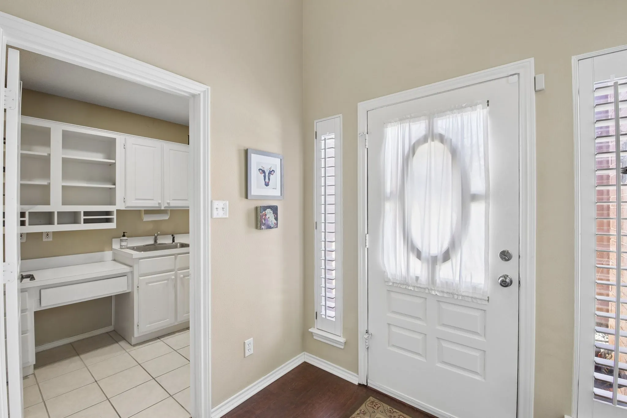 Entryway featuring a paneled door with an oval glass insert, flanked by side windows with slat blinds