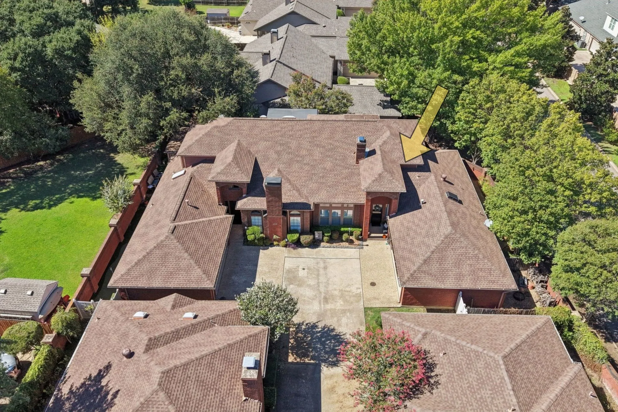 Expansive property featuring a brown shingle roof, brick exterior, and a concrete driveway