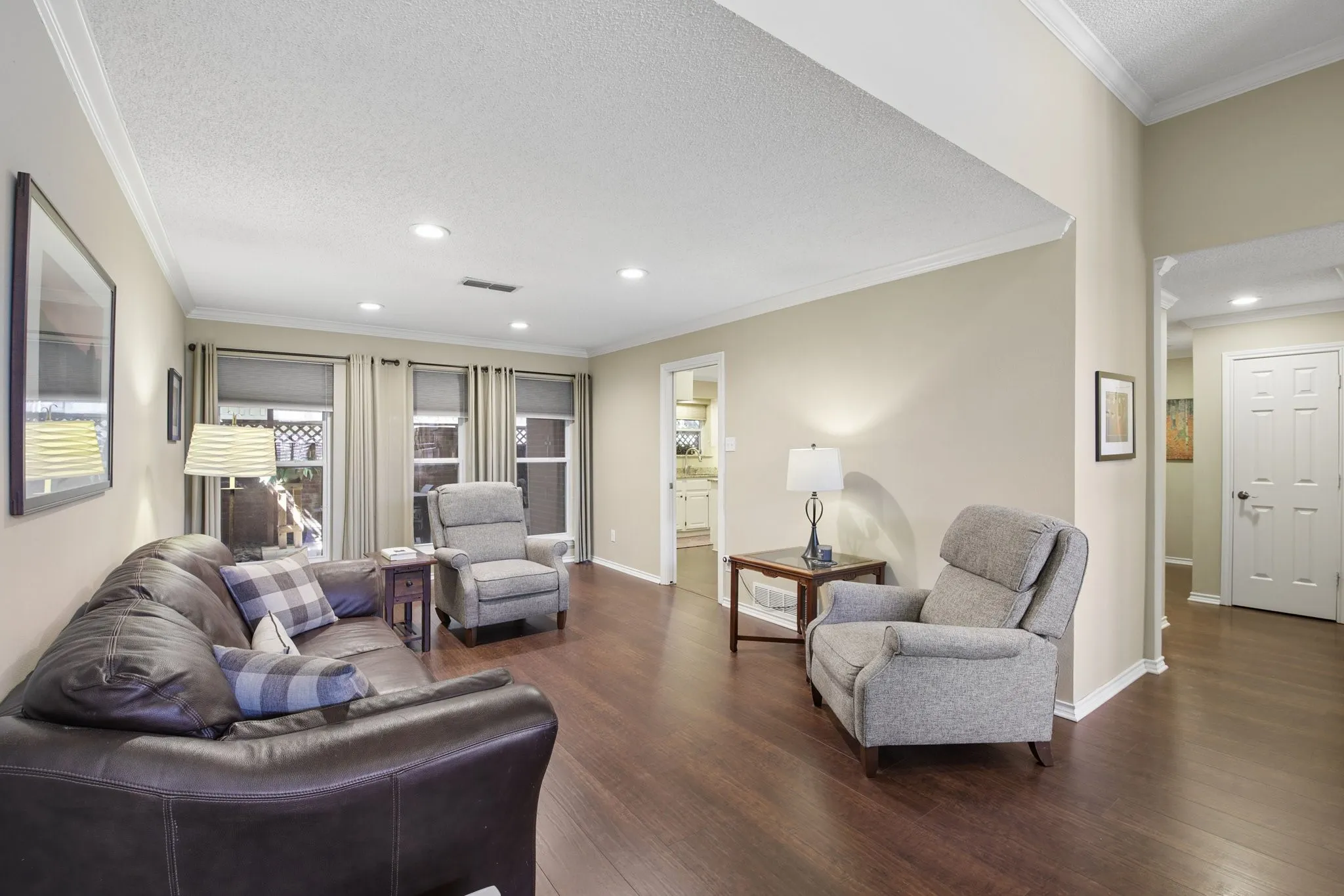 Hardwood flooring throughout, recessed ceiling lighting, crown molding, and multiple windows with roller shades
