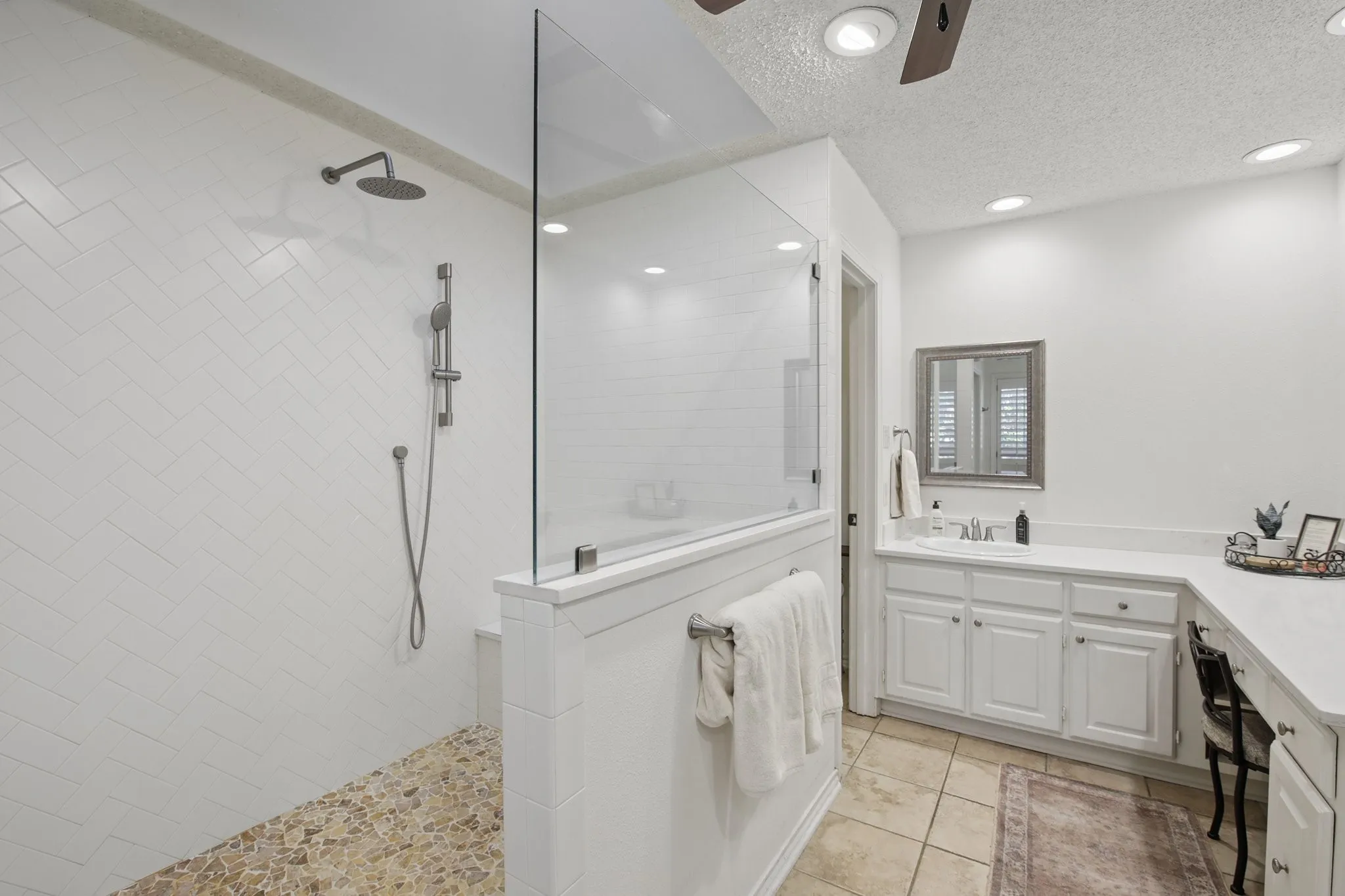 Walk-in shower with herringbone tile walls and pebble flooring