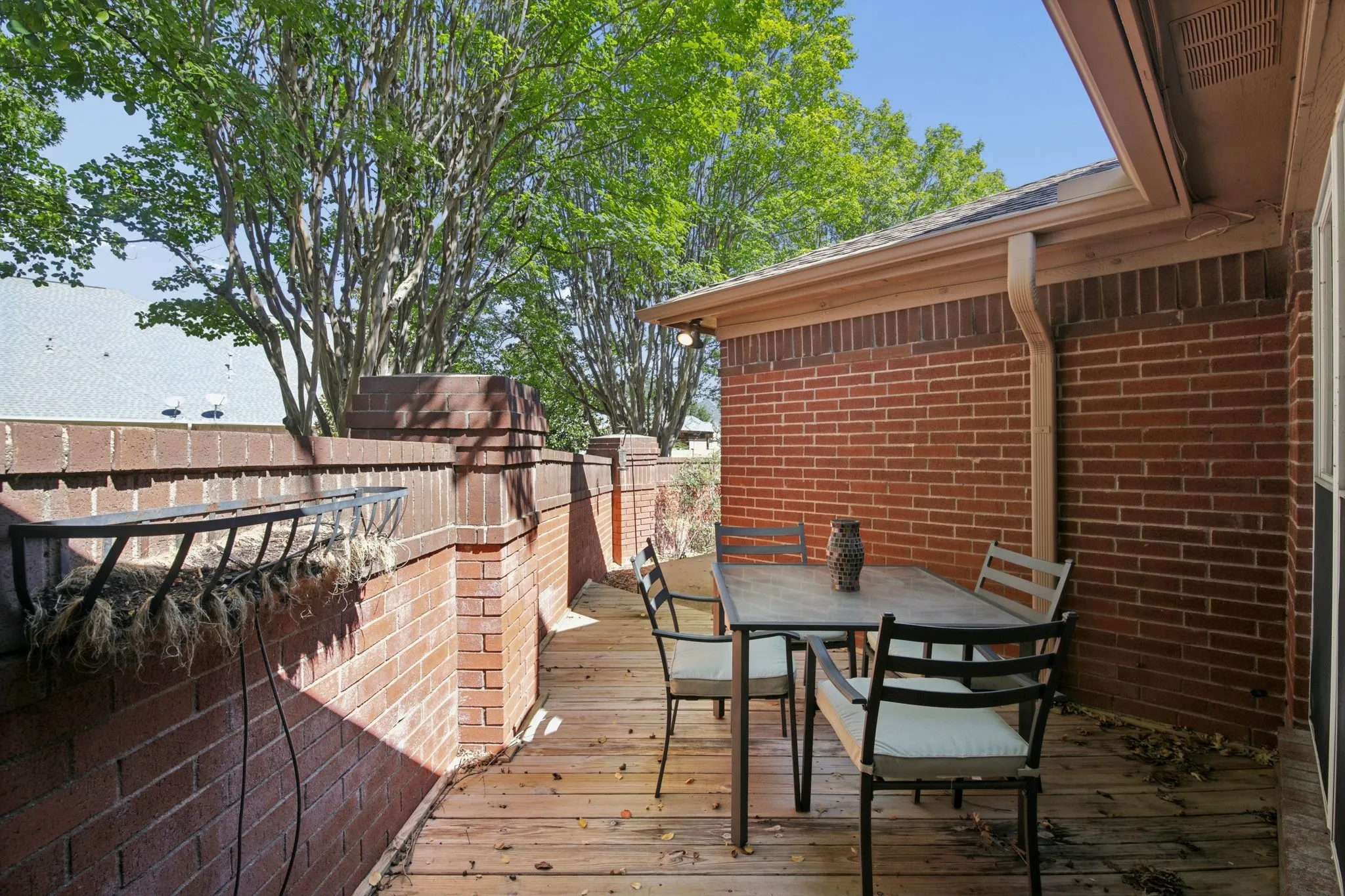 Wood-finish deck with a brick half-wall and brick exterior
