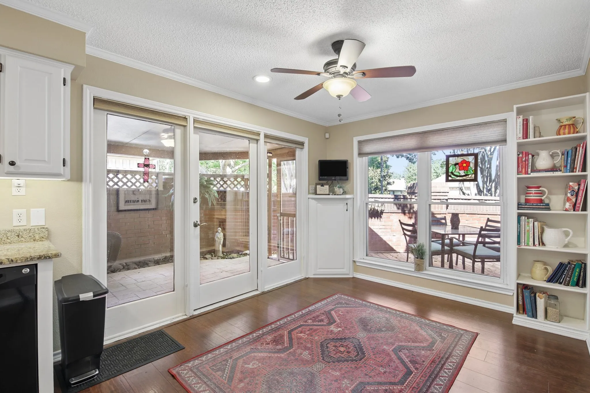 Wood flooring, built-in shelving, white cabinetry, and a ceiling fan with integrated lighting