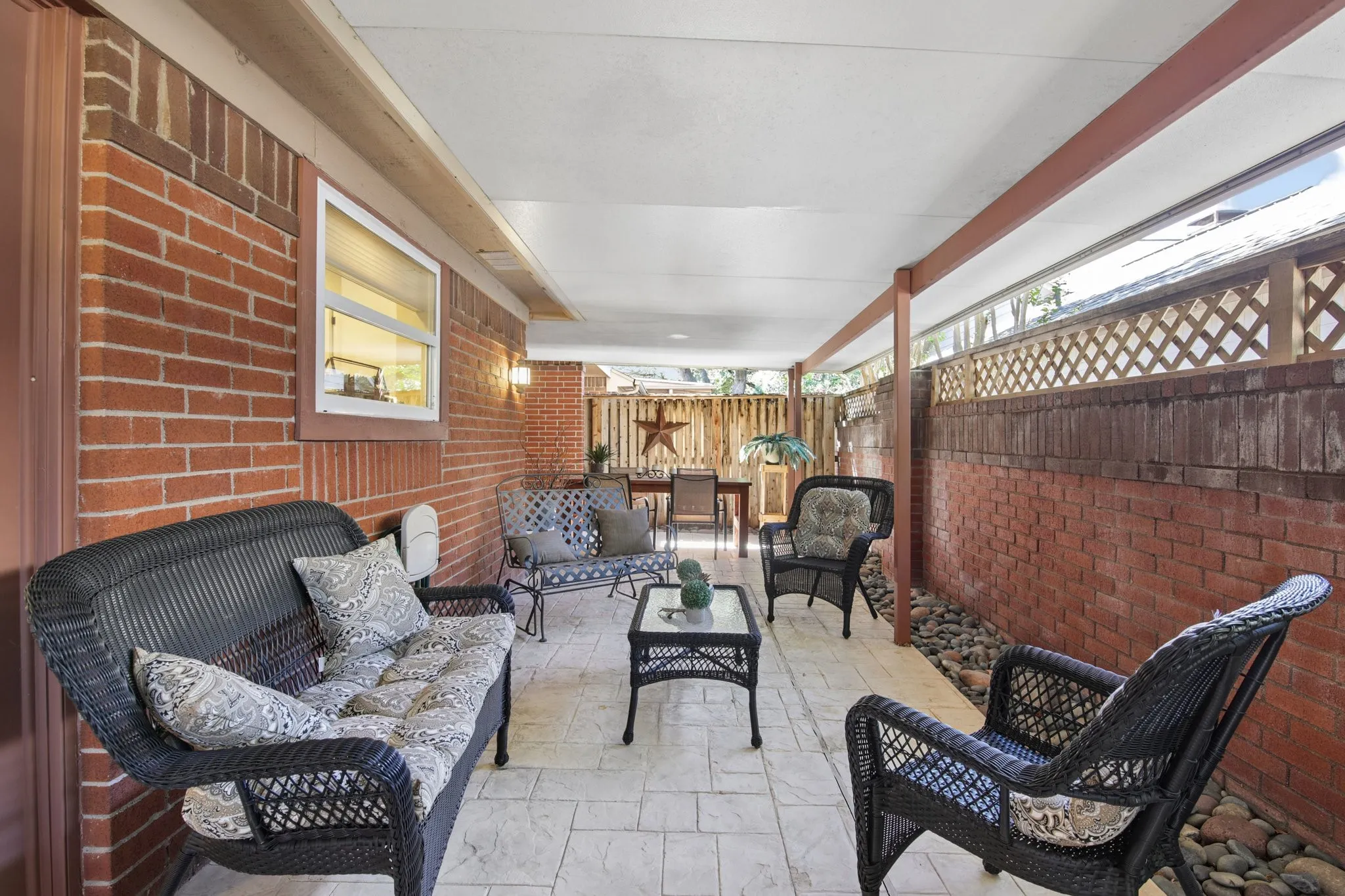 Covered patio featuring a stamped concrete surface, brick exterior wall, and wood lattice privacy screening